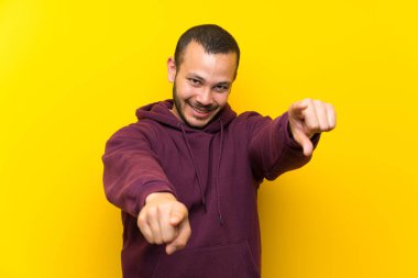 Gülümseyen iken sarı duvar noktaları parmak üzerinde Sweatshirt ile Kolombiyalı adam