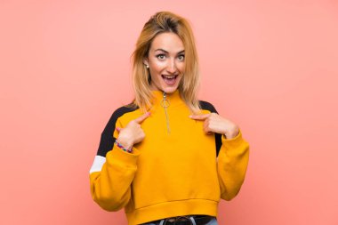 Yüzünde sürpriz bir ifade olan, pembe bir geçmişi olan genç sarışın kadın.