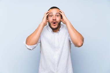 Sürpriz ifade ile izole mavi duvar üzerinde Kolombiyalı adam