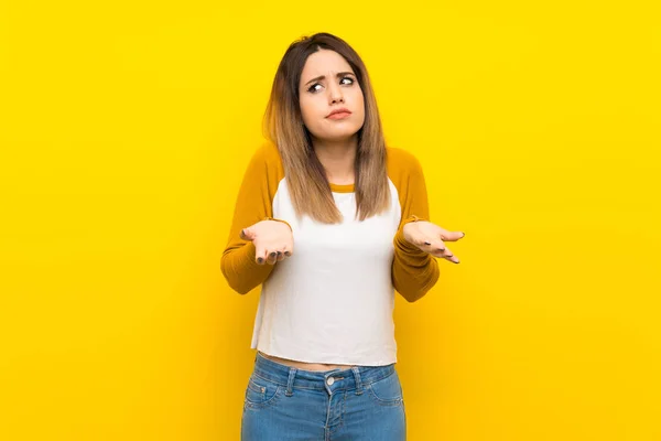 Mooie Jonge Vrouw Geïsoleerde Gele Muur Maken Twijfels Gebaar — Stockfoto