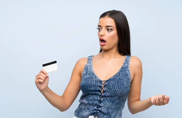 Joven Mujer Sobre Aislada Pared Azul Sosteniendo Una Tarjeta Crédito —  Fotos de Stock