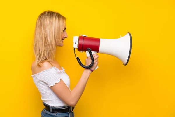 Jonge Blonde Vrouw Geïsoleerde Gele Muur Schreeuwen Door Een Megafoon — Stockfoto