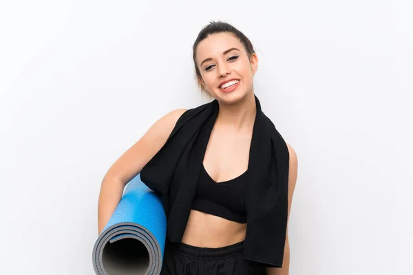 Young sport woman over white wall with mat