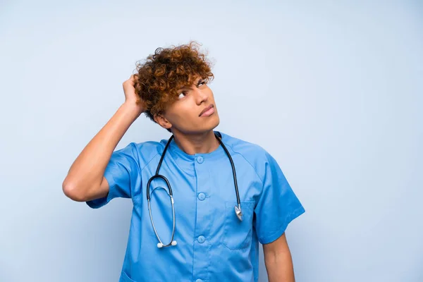 Surgeon doctor african american man having doubts and with confuse face expression