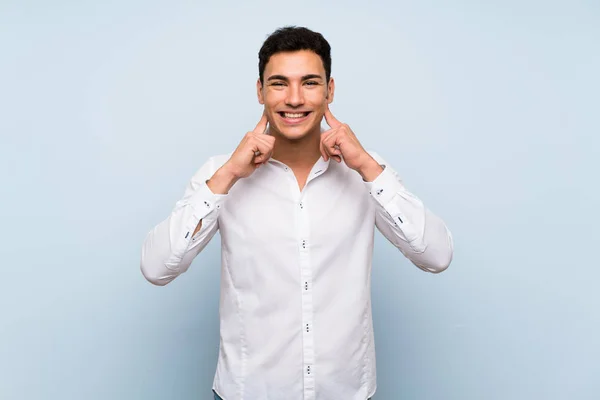 Handsome man over blue wall smiling with a happy and pleasant expression