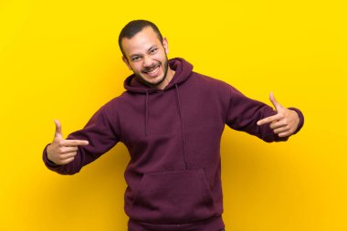Sarı duvar gururlu ve kendinden memnun üzerinde Sweatshirt ile Kolombiyalı adam