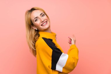 İzole edilmiş pembe arka planı olan genç sarışın kadın.