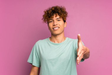 İyi bir anlaşma sonra izole mor duvar el sallama üzerinde genç Afrikalı Amerikalı adam