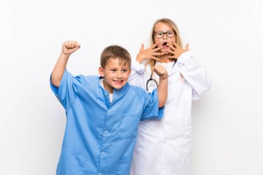 Küçük kardeşler izole beyaz duvar üzerinde doktorlar olmak için oynuyor