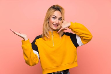 İzole pembe arka plan üzerinde genç sarışın kadın telefon jest yapma ve şüphe