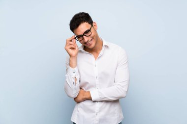 Gözlük ve mutlu ile mavi duvar üzerinde Yakışıklı adam