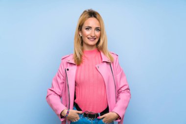 Genç Sarışın kadın pembe ceket ile izole mavi arka plan gülüyor