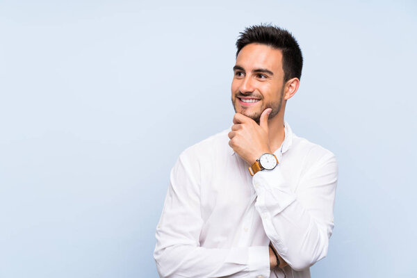 Handsome young man over isolated blue background looking to the side