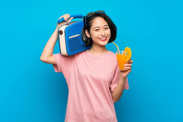 Азиатская молодая женщина на изолированном синем фоне держит радио — стоковое фото