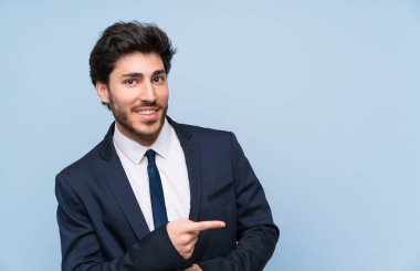 İzole mavi duvar üzerinde işadamı yan parmak işaret