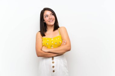 Young Mexican woman over isolated wall looking up while smiling