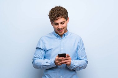 Sarışın adam mavi duvar mobil ileti gönderme