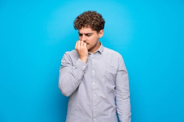 Sarışın adam mavi duvarın şüpheleri üzerinden