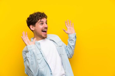 Sarışın adam sürpriz yüz ifadesi ile izole sarı duvarın üzerinden