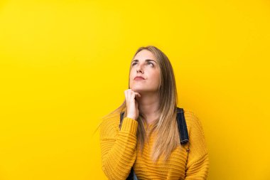 Önlüklü kadın izole edilmiş sarı duvarın üzerinde duruyor ve bir fikir düşünüyor.