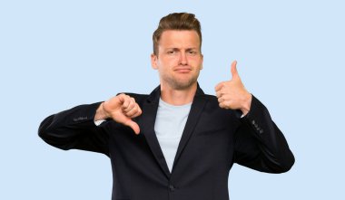 Sarışın yakışıklı adam iyi-kötü işareti yapıyor. Evet ya da değil arasında kararsız