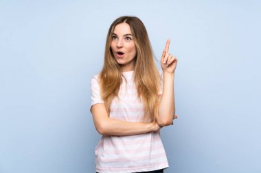 Soyutlanmış mavi arka planda genç bir kadın bir fikir düşünüyor.