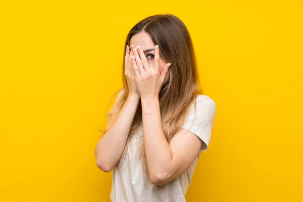 Sarı Duvardan Izole Edilmiş Genç Bir Kadın Gözlerini Kapatıyor Parmaklarından — Stok fotoğraf
