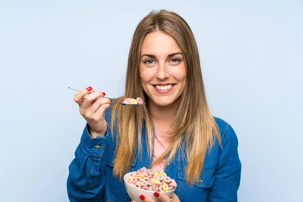 Glückliche junge Frau mit Schale Getreide über isolierter blauer Wand — Stockfoto