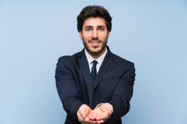 Bir reklam eklemek için avuç üzerinde copyspace hayali tutan izole mavi duvar üzerinde İşadamı