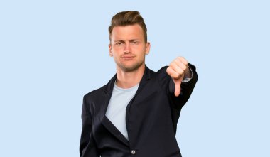 Sarışın yakışıklı adam olumsuz ifade ile başparmak aşağı gösteren