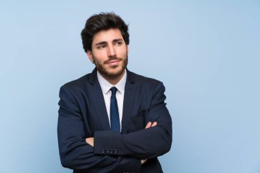 İzole mavi duvar üzerinde işadamı omuzkaldırma sırasında şüphe jest yapma