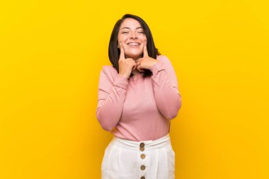 Young Mexican woman over isolated yellow background smiling with a happy and pleasant expression