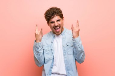 Pembe duvar üzerinde sarışın adam kaya jest yapma