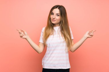 Soyutlanmış pembe duvarın üzerindeki genç kadın yan taraftaki kuşkuları işaret ediyor.