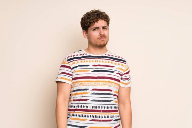 Üzgün ve depresif ifade ile izole duvar üzerinde Blonde adam