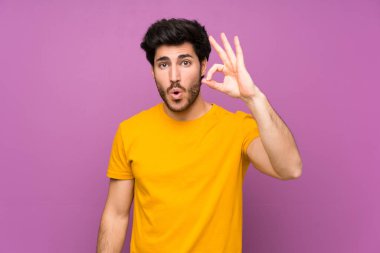 Izole mor duvar üzerinde Yakışıklı şaşırttı ve ok işareti gösteren