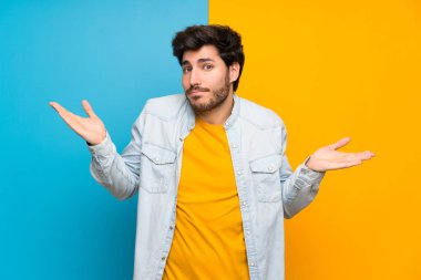 Izole renkli arka plan üzerinde yakışıklı şüpheler jest yapma