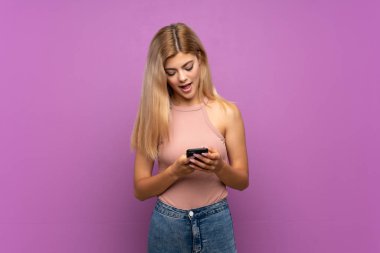 Cep telefonu ile bir mesaj göndererek izole mor arka plan üzerinde Genç kız
