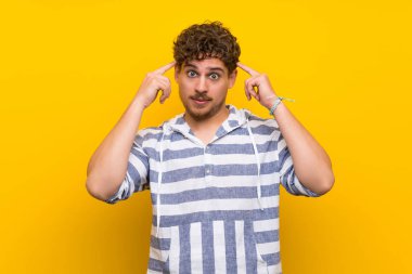 Sarı duvar üzerinde sarışın adam şüpheleri ve düşünme sahip