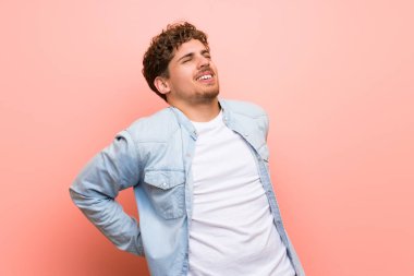 Bir çaba için sırt ağrısı muzdarip pembe duvar üzerinde Blonde adam