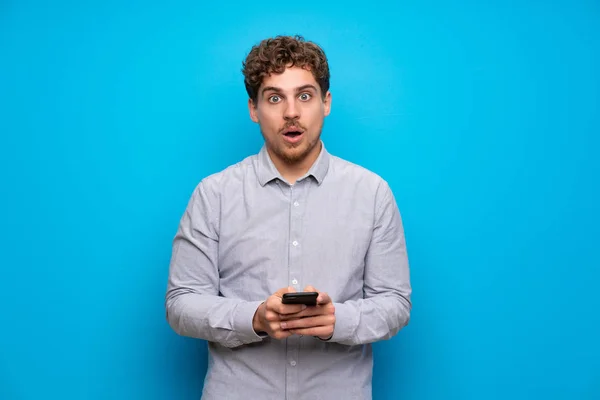 Blonde Man Blue Wall Surprised Sending Message — Stock Photo, Image