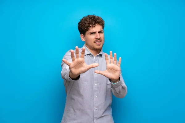 Blond Mann Blå Vegg Nervøs Strekke Hender Mot Fronten – stockfoto