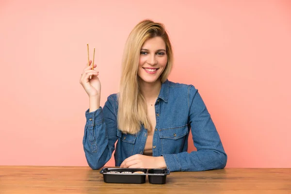 Young blonde woman eating sushi