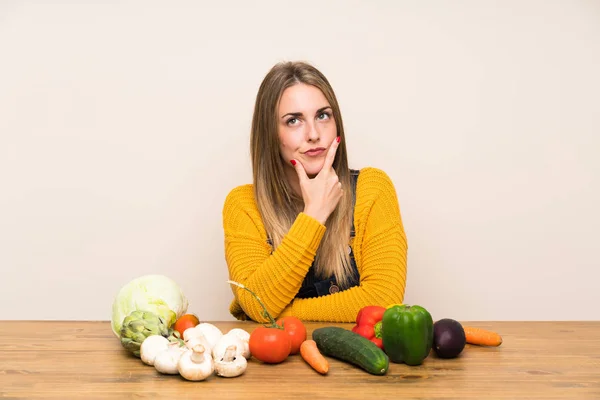 Woman with lots of vegetables standing and thinking an idea