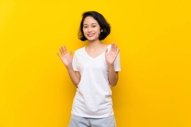 Asya genç kadın üzerinde izole sarı duvar gülümseyen