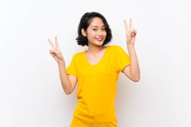 Izole beyaz arka plan üzerinde Asyalı genç kadın iki eliyle zafer işareti gösteren