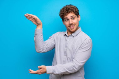 Sarışın adam boşaltmak tutan mavi duvarın üzerinden bir reklam eklemek için