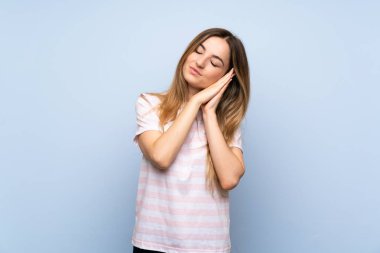 İzole mavi arka plan üzerinde genç kadın dorable ifade uyku jest yapma