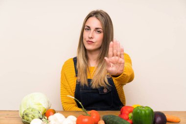 Bir sürü sebzeli kadın elleriyle dur hareketi yapıyor.