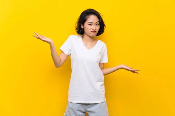 Asiática Joven Mujer Sobre Aislado Amarillo Pared Infeliz Para Entender —  Fotos de Stock